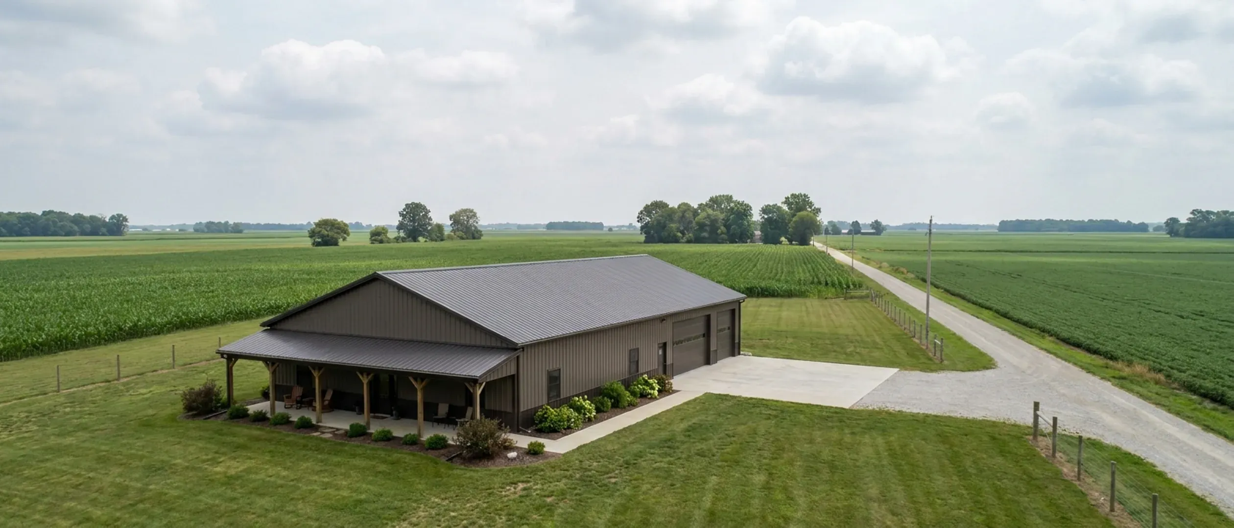A completed barndominium with a covered entry porch and an attached shop bay, photographed in flat overcast daylight.