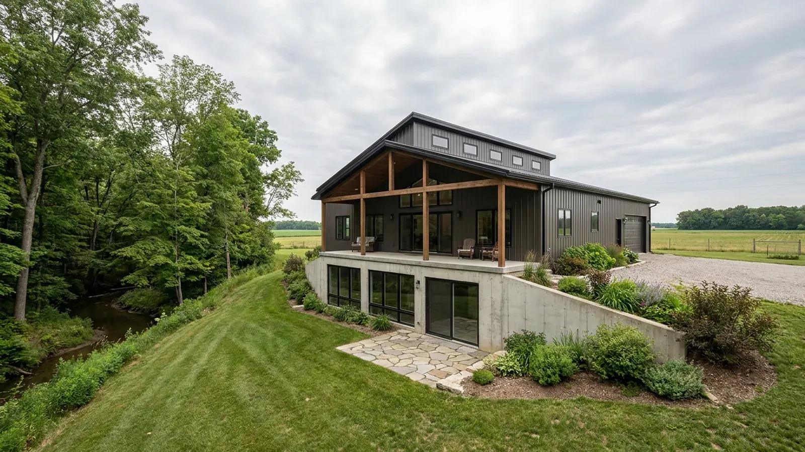 A barndominium with a walkout basement built into a sloping lot, the lower level opening onto a patio at grade.